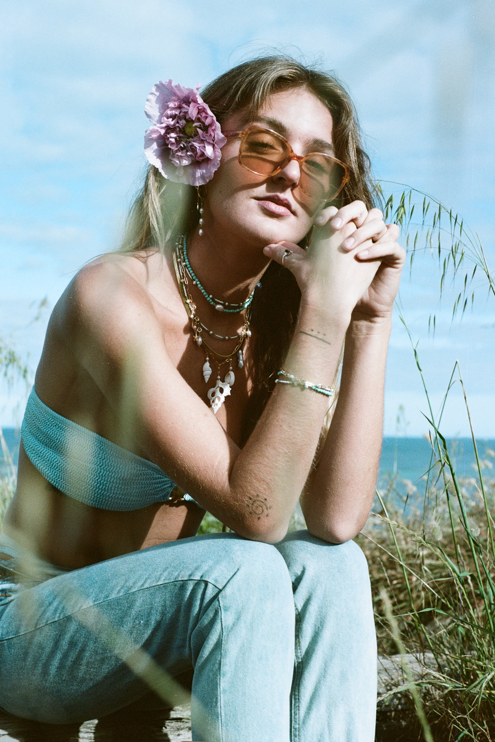 Woman in sunglasses near beach with flower in hair