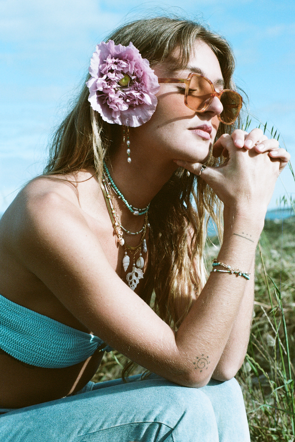 Woman outdoors, wearing sunglasses and flower in hair.
